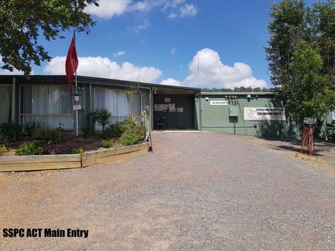 Gravel forecourt and garden beds at the SSPC ACT main entry, with the club flag